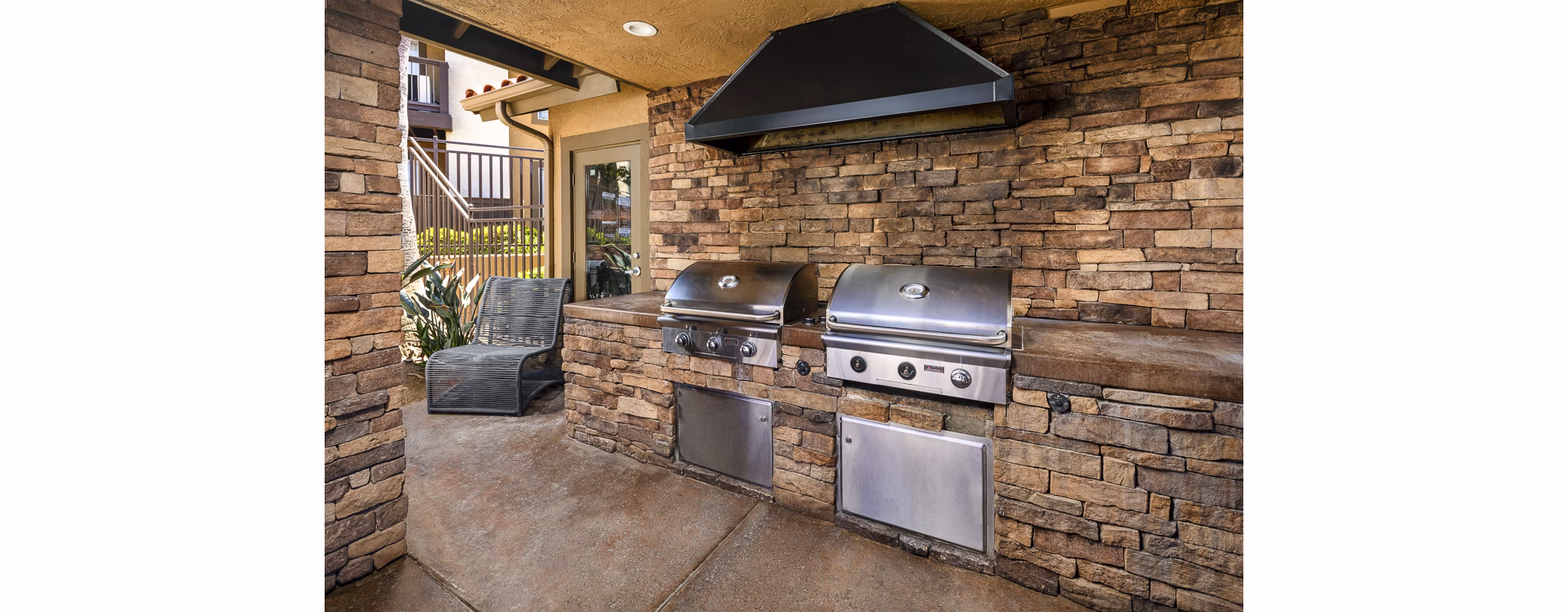 Bella Terra Apartments: Outdoor grill area with seating and lush landscaping, perfect for social gatherings and leisure