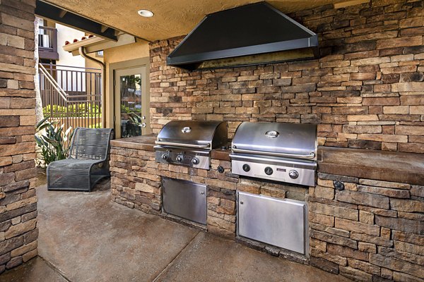 Bella Terra Apartments: Outdoor grill area with seating and lush landscaping, perfect for social gatherings and leisure