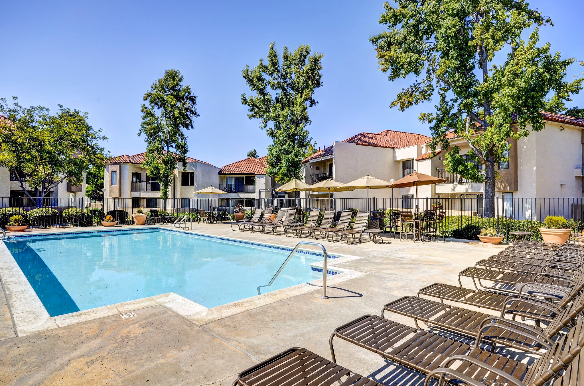 Resort-style pool with loungers at The Casas Apartments offers luxurious relaxation in a sophisticated setting