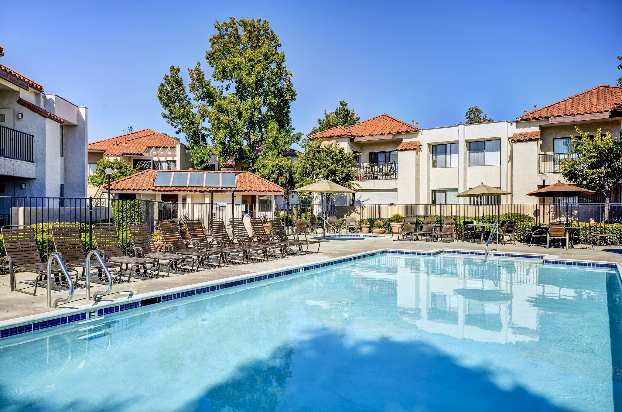 Relaxing outdoor pool at The Casas Apartments with sun loungers and lush landscaping
