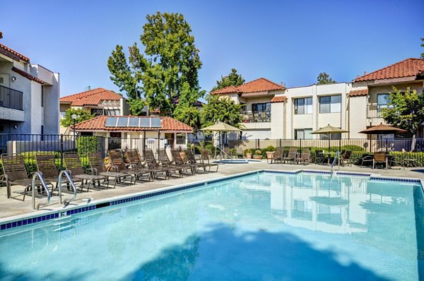 Relaxing outdoor pool at The Casas Apartments with sun loungers and lush landscaping