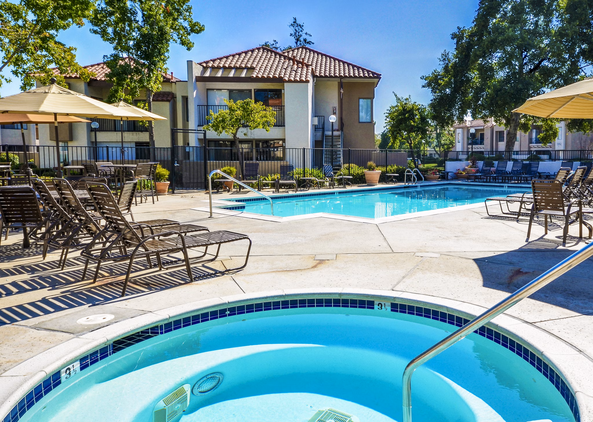Relaxing poolside with hot tub at The Casas Apartments, a luxury community by Greystar