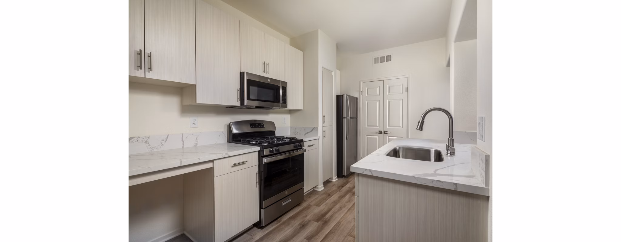Modern kitchen featuring stainless steel appliances and stone countertops at Casoleil Apartments