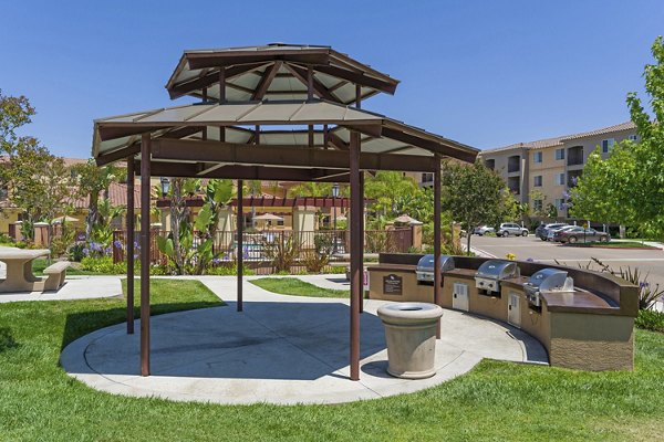 Outdoor grill area at Greenfield Village Apartments with modern seating and lush landscaping