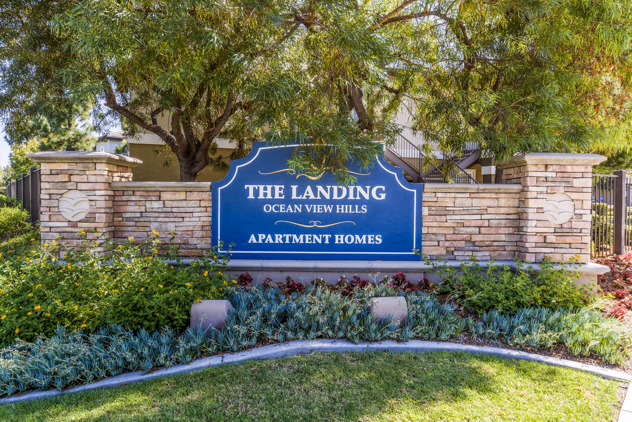 The Landing Ocean View Hills Apartment Homes sign with lush landscaping in front of the entrance