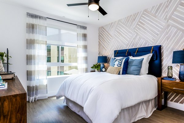 The Lofts at Carlsbad Village: Bright bedroom with modern furnishings and scenic views in luxury Carlsbad apartments