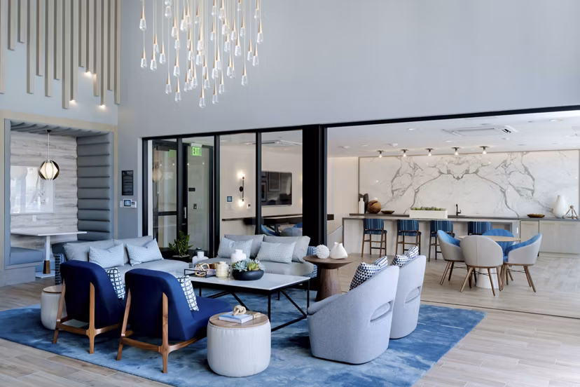 Elegant clubhouse lobby with modern decor at The Lofts at Carlsbad Village Apartments, featuring cozy seating and vibrant art pieces