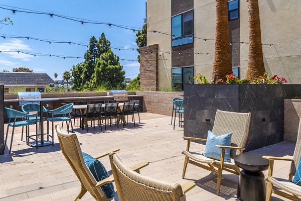 Outdoor grill area with seating at The Lofts at Carlsbad Village Apartments, perfect for gatherings and barbecues