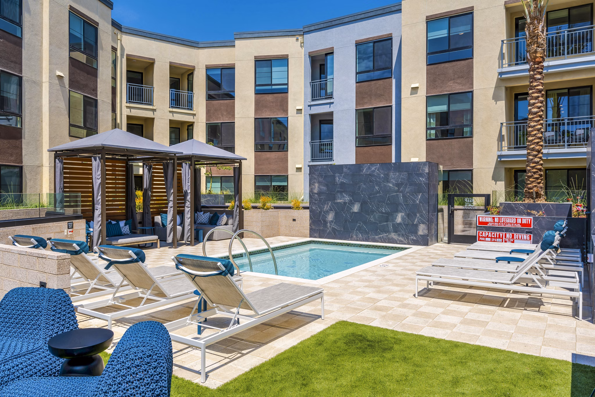 Resort-style pool with lounge seating at The Lofts at Carlsbad Village Apartments