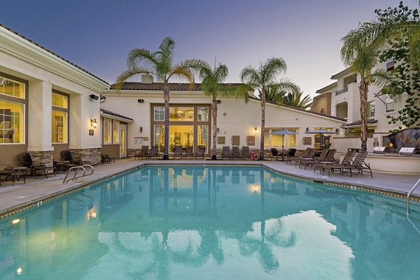 Luxurious pool area at Rosina Vista Apartments with sun loungers and palm trees, offering a serene retreat for residents