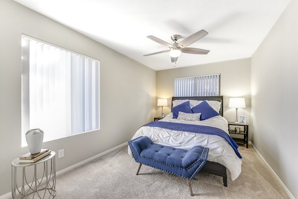 Cozy bedroom with large windows and neutral decor at Santee Villas Apartments