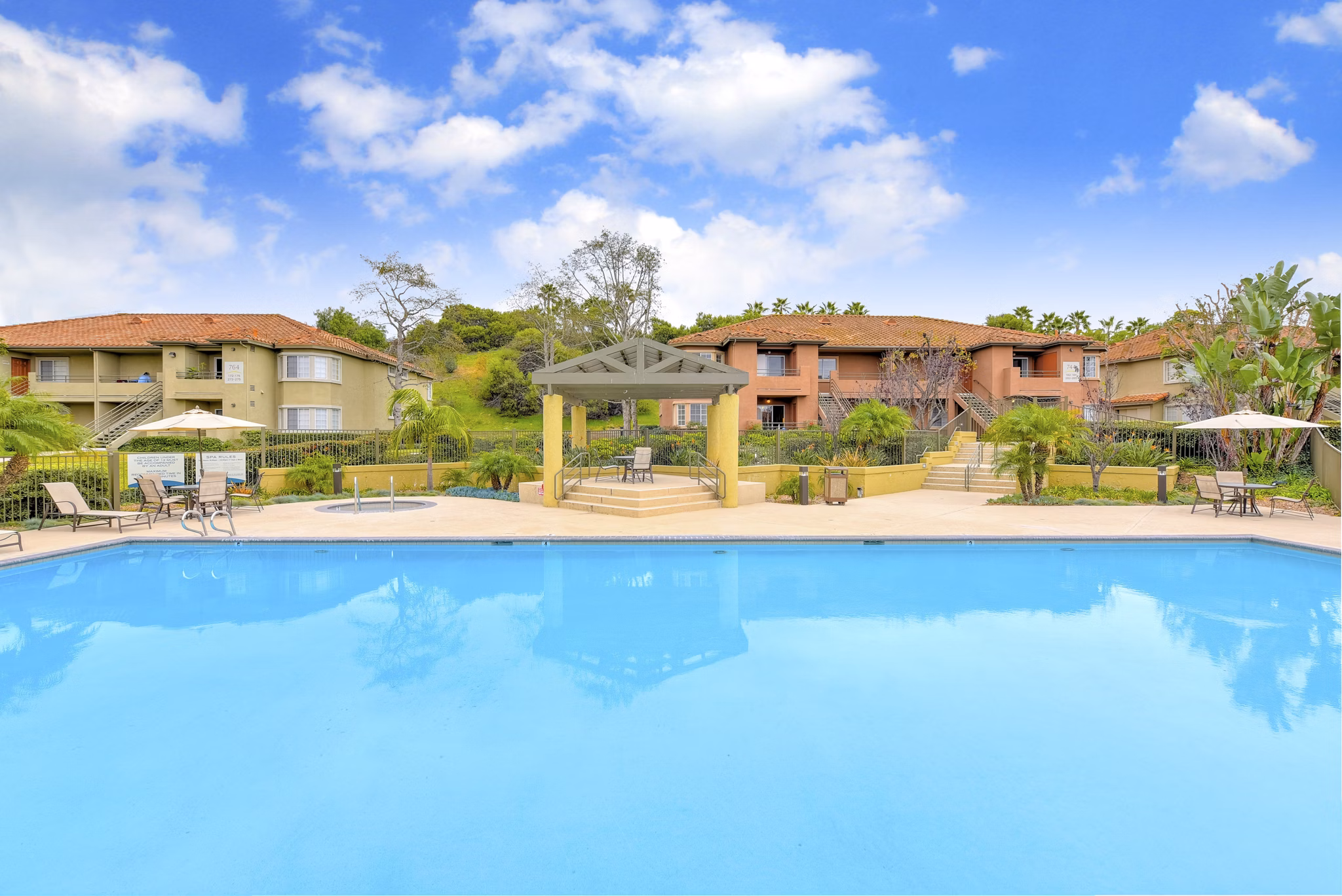 Relaxing pool area with lounge chairs at Sunbow Villas Apartments