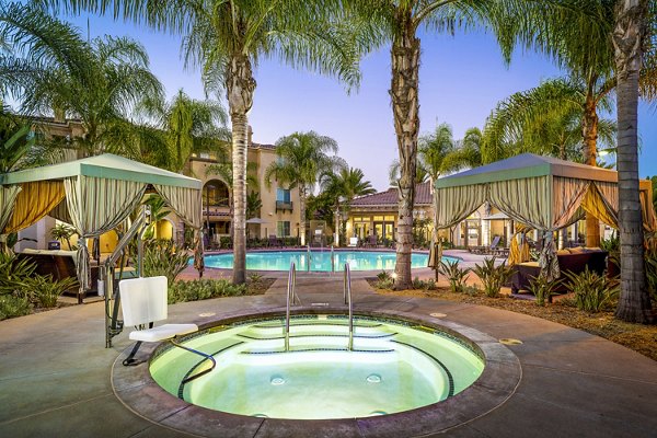 Luxurious pool at Tavera Apartments with sun loungers and lush landscaping