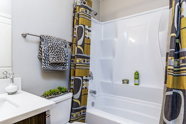 Bathroom with modern fixtures and large mirror at Village Square Apartments, a luxury community by Greystar