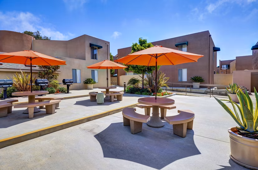 Outdoor grill area with modern seating at Village Square Apartments, perfect for gatherings and entertaining in a luxury setting