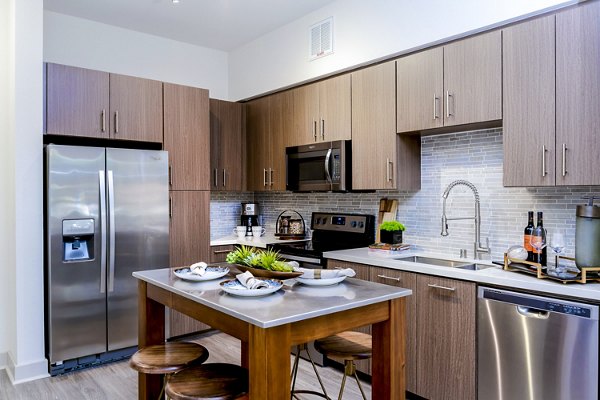 Modern kitchen with stainless steel appliances and granite countertops at Vora Mission Valley East Apartments in San Diego