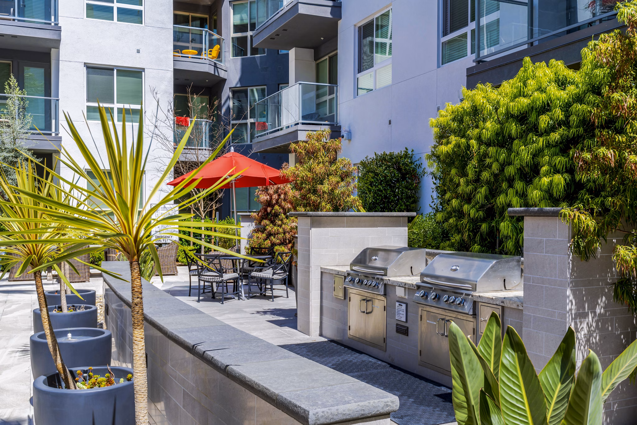 Outdoor grill area at Vora Mission Valley East Apartments with modern seating and lush landscaping