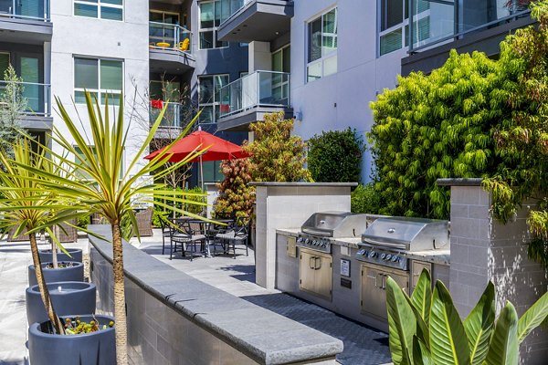 Outdoor grill area at Vora Mission Valley East Apartments with modern seating and lush landscaping