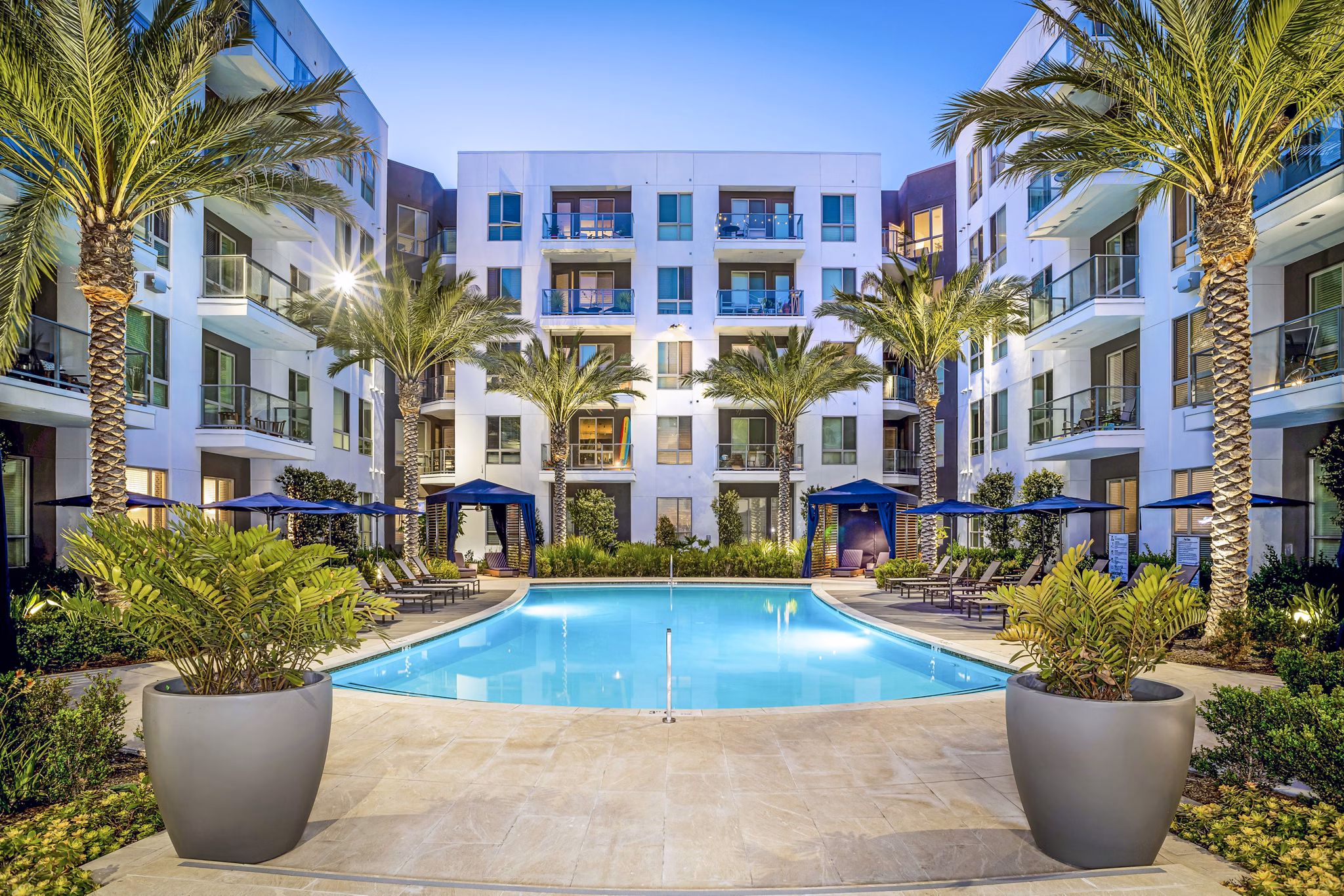 Stylish pool at Vora Mission Valley East Apartments with lounge chairs and lush landscaping, ideal for relaxation in San Diego
