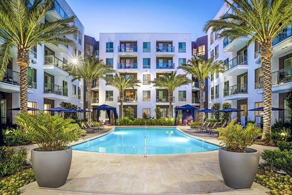 Stylish pool at Vora Mission Valley East Apartments with lounge chairs and lush landscaping, ideal for relaxation in San Diego