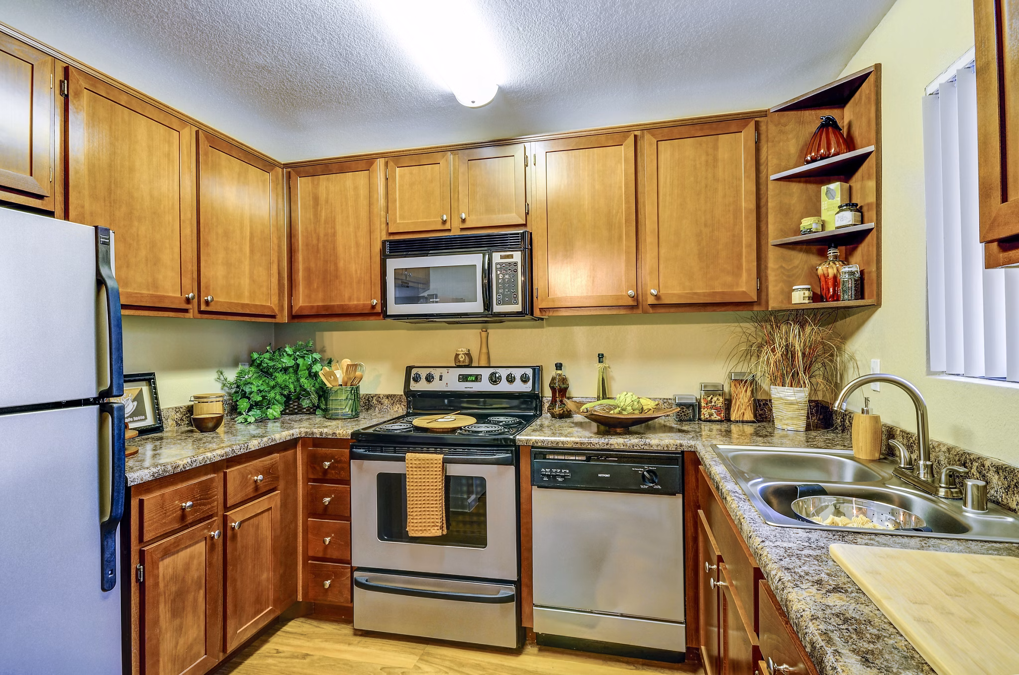 Modern kitchen featuring granite countertops and stainless steel appliances in Shadowridge Woodbend Apartments