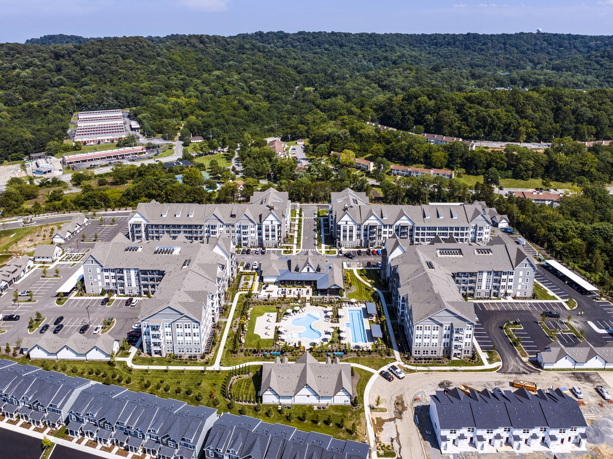 Modern swimming pool area with red Adirondack chairs and luxury apartments in the background