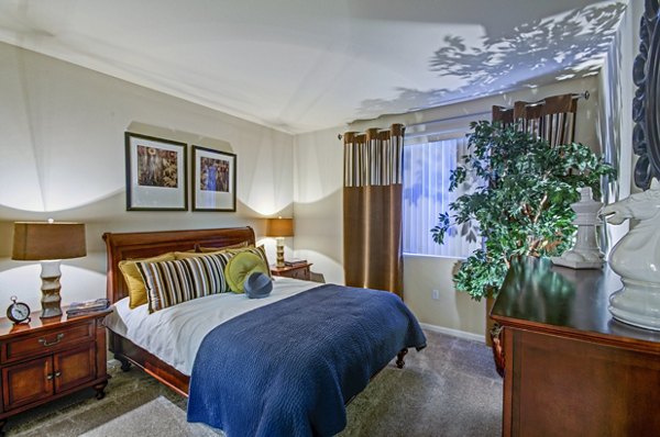 Ridgestone Apartments: Cozy bedroom featuring modern furnishings and natural light, ideal for luxury living