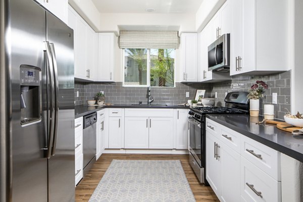 Sleek kitchen featuring stainless steel appliances and granite countertops in Sorano Apartments