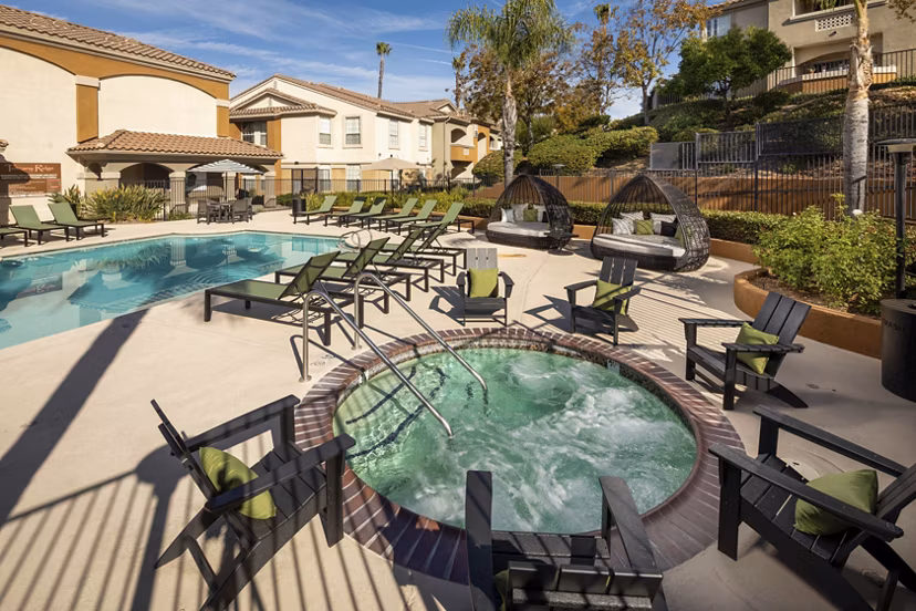 Resort-inspired pool with sun loungers at Tuscany Ridge Apartments, offering luxury living and leisure in a serene setting