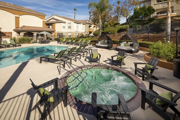 Resort-inspired pool with sun loungers at Tuscany Ridge Apartments, offering luxury living and leisure in a serene setting
