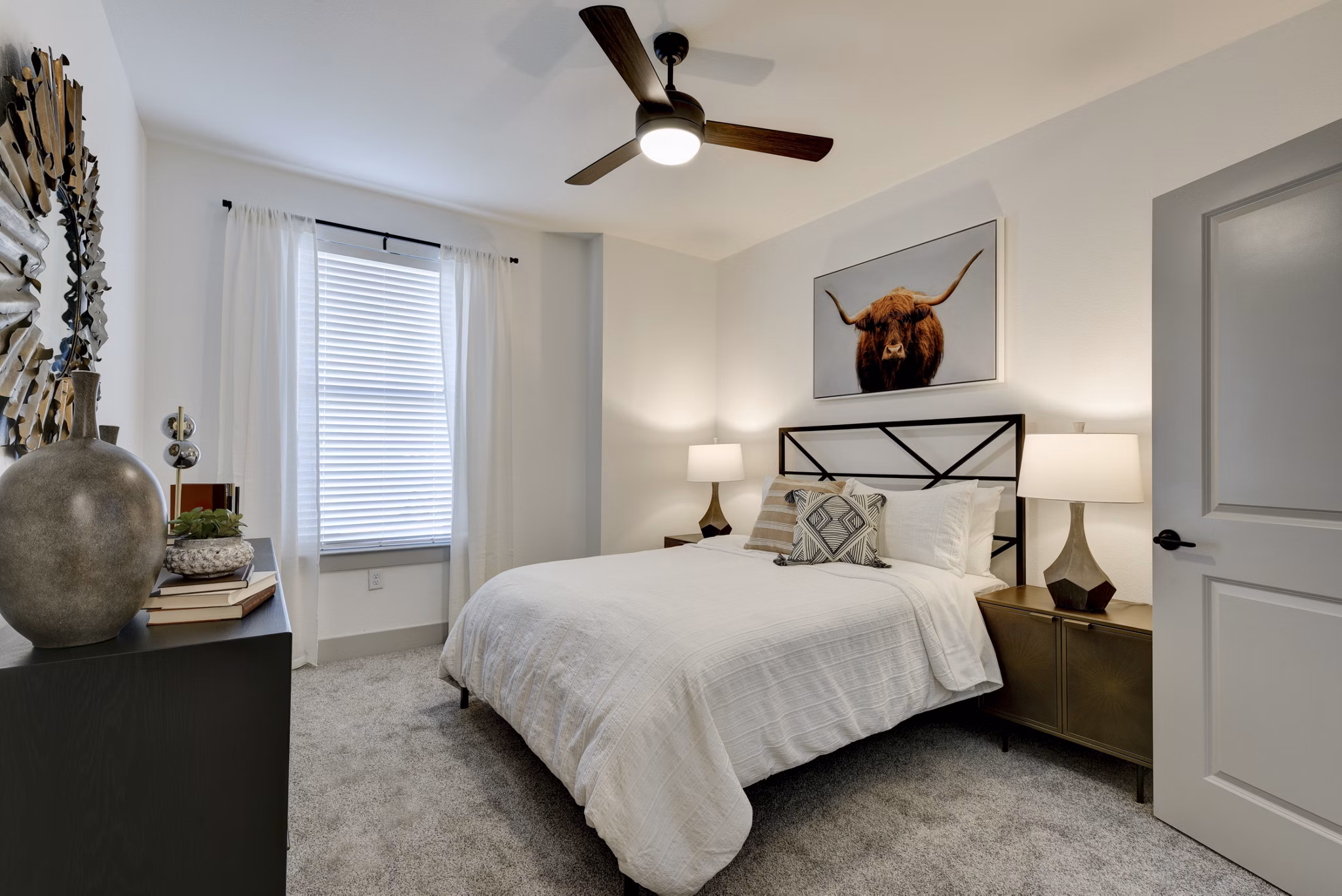 Cozy bedroom featuring minimalist design and large windows at Arbolada Apartments