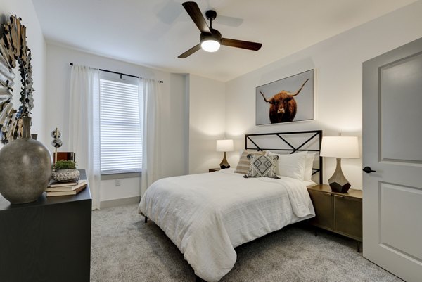 Cozy bedroom featuring minimalist design and large windows at Arbolada Apartments