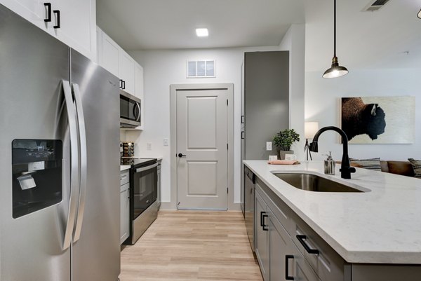 Modern kitchen with stainless steel appliances and granite countertops in Arbolada Apartments