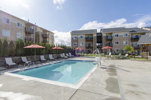 Relaxing pool area at Britton Place Apartments with lounge seating and greenery, perfect for unwinding in a luxury setting