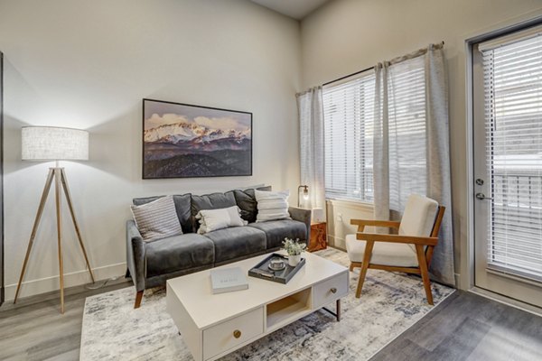 Cozy living room with modern decor and large windows at The Plaza at Pikes Peak Apartments