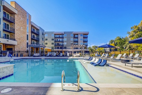 Stylish outdoor pool with sun loungers at The Plaza at Pikes Peak Apartments