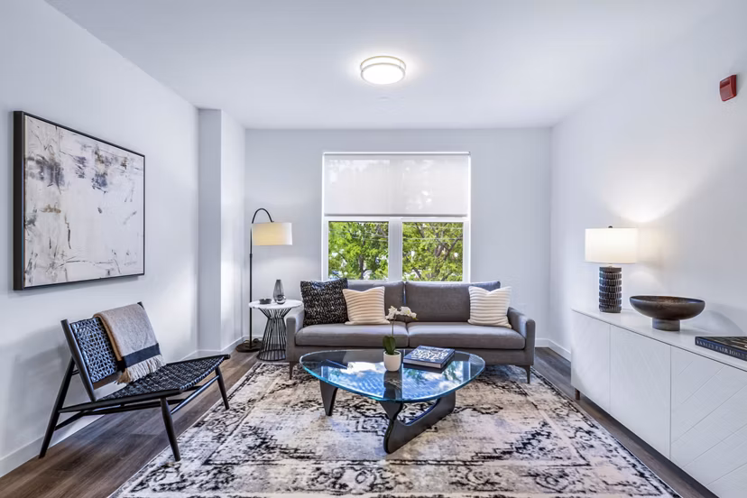 Modern living room with cozy seating and large windows at The Park at Woodbridge Station Apartments