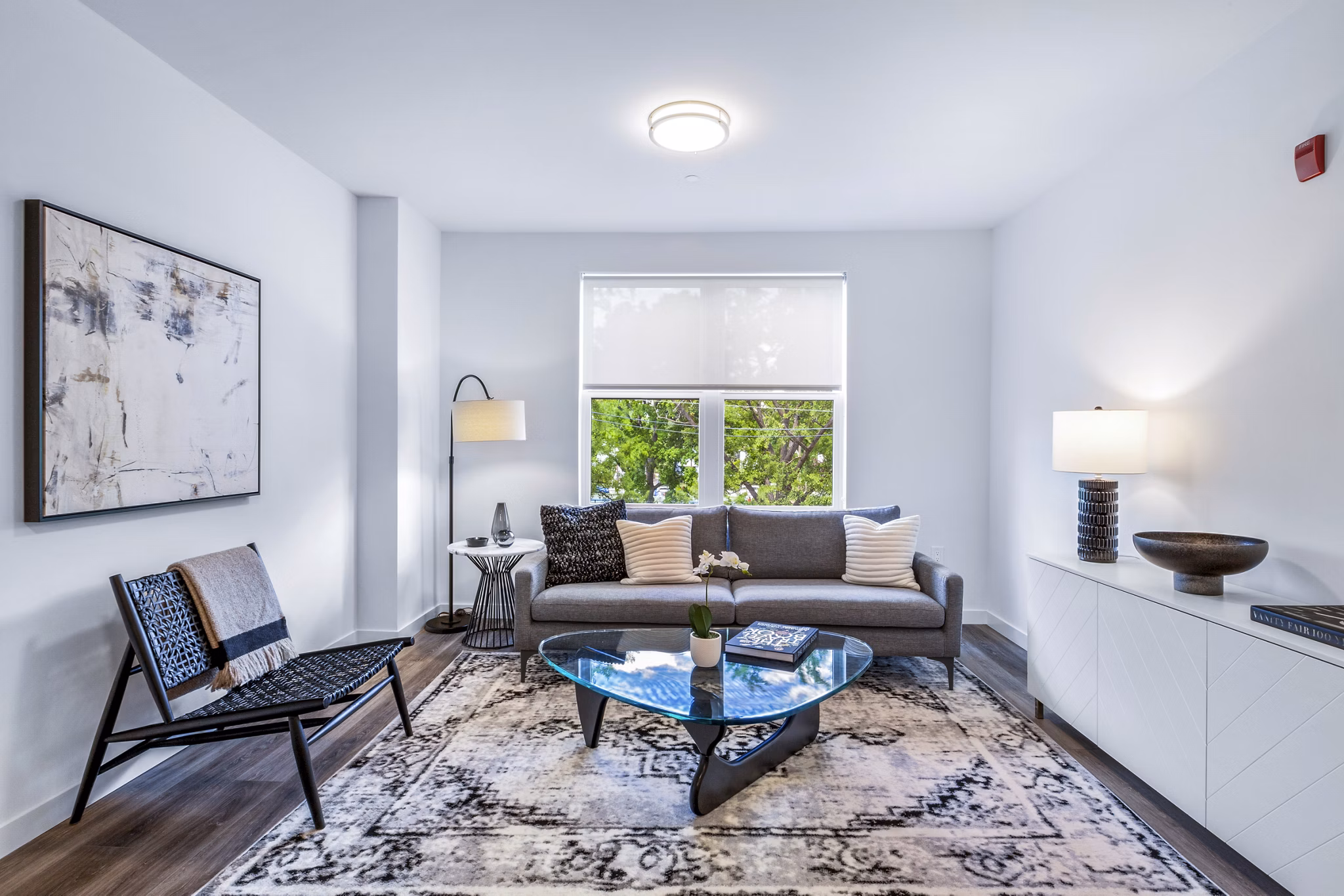Modern living room with cozy seating and large windows at The Park at Woodbridge Station Apartments