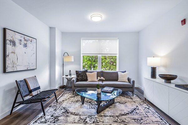 Modern living room with cozy seating and large windows at The Park at Woodbridge Station Apartments