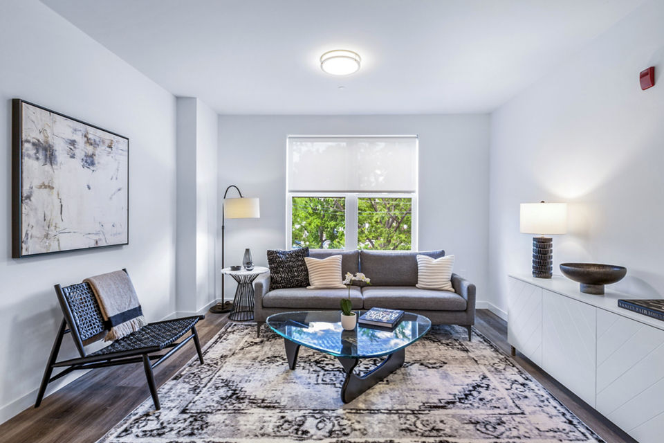 Modern living room with cozy seating and large windows at The Park at Woodbridge Station Apartments