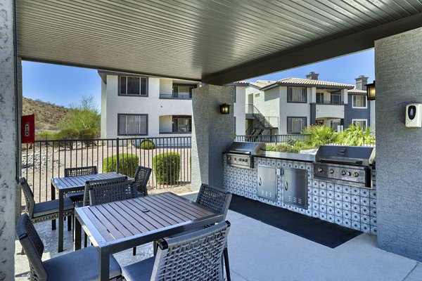 Outdoor grill area with picnic tables and lush landscape at Mountainside Apartments