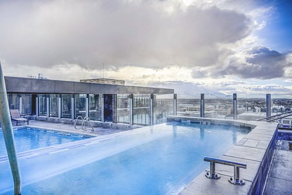 Sunlit outdoor pool with lounge chairs at The Charles Apartments, luxury living in a serene setting