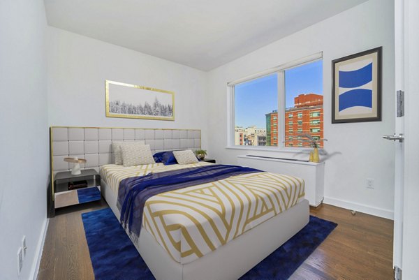 Modern bedroom with plush bedding and large windows at 1209 Dekalb Apartments, a Greystar luxury community