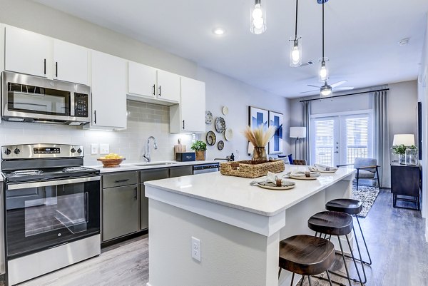 Open-concept kitchen with stainless steel appliances at Moderno Apartments, showcasing luxury finishes and contemporary design