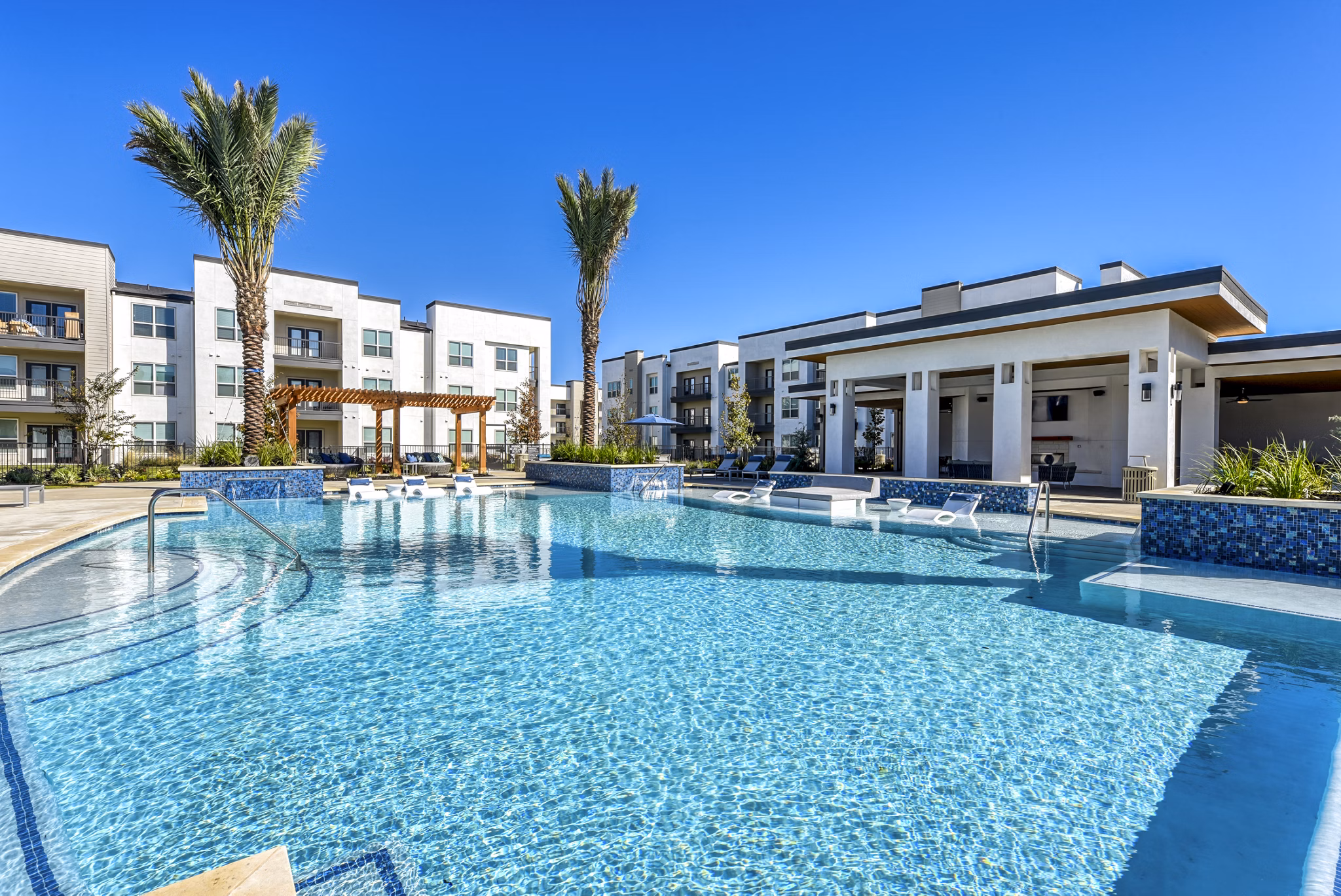Luxury pool with lounge chairs at Moderno Apartments, offering relaxation and recreation in a vibrant community setting