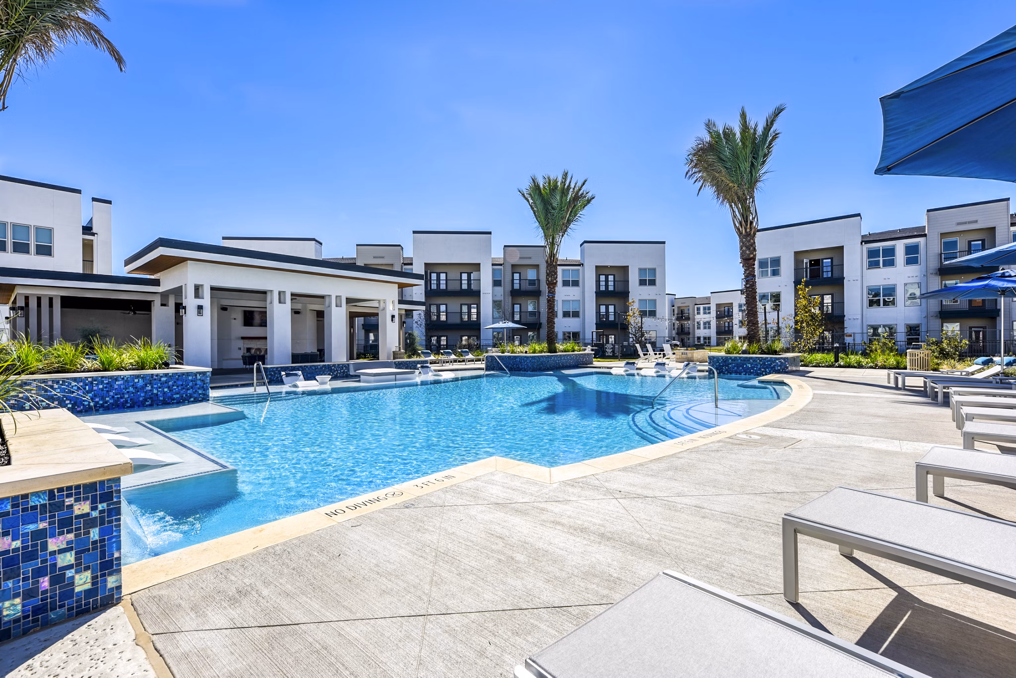 Refreshing swimming pool area with lounge chairs and palm trees at luxury apartments