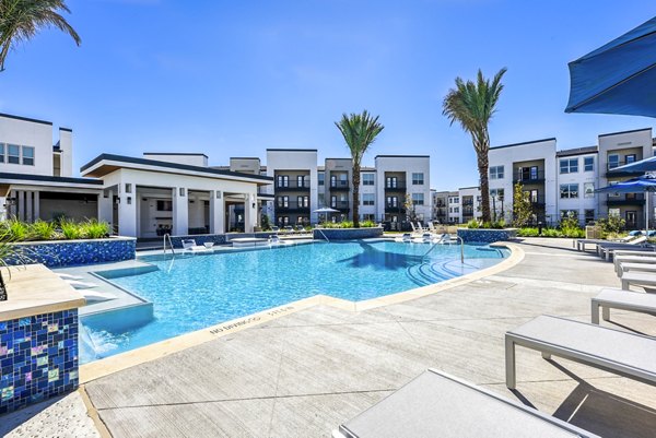 Refreshing swimming pool area with lounge chairs and palm trees at luxury apartments