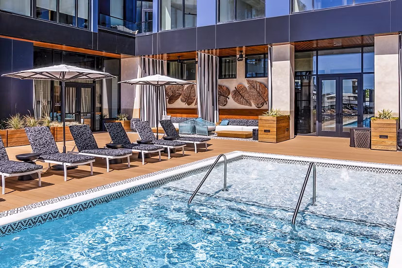 Modern pool with sleek lounge chairs at Fallyn Apartments, offering luxury leisure amenities