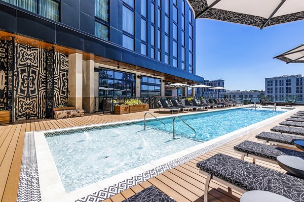 Infinity pool with lush greenery at Fallyn Apartments, luxury living by Greystar in a serene setting