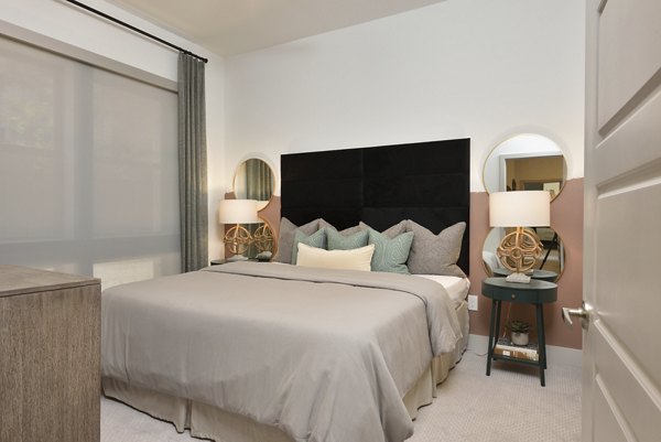 Cozy bedroom with large windows at The Flats at West Alabama Apartments, offering modern luxury living in an ideal Houston location